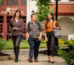 Three Students walking in front of the Feliciano School of Business building at Montclair State University