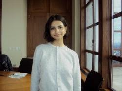 female student standing next to windows in front of a table