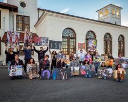 Students Holding Photojournalism Project Photos outside of School of Communication Building